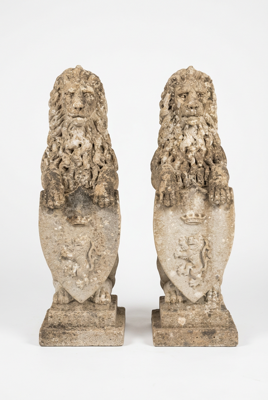 Pair of weathered stone garden lions holding heraldic shields.