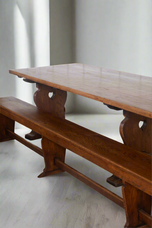 Oak refectory table and bench with shaped wooden supports and small heart-shaped cutouts.