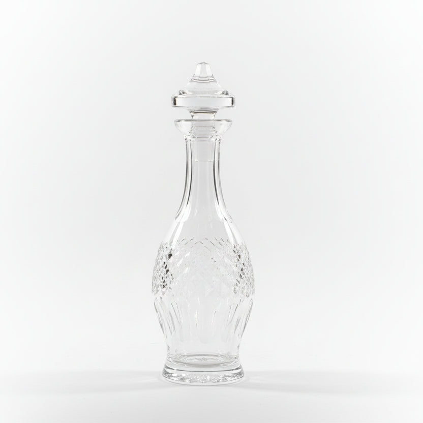 Clear glass vase on a wooden surface with ornate metal objects in the background