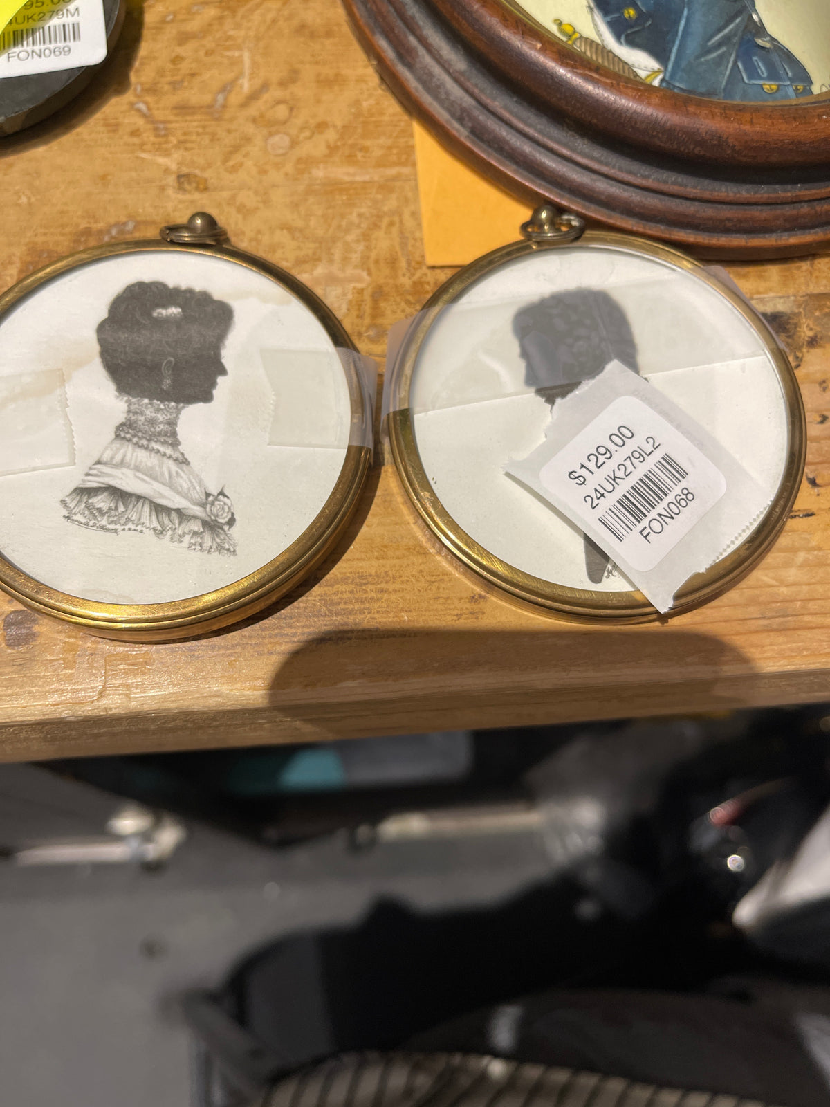 A pair of silhouette portraits of a gentleman and lady in small brass oval frames, displayed on a table.
