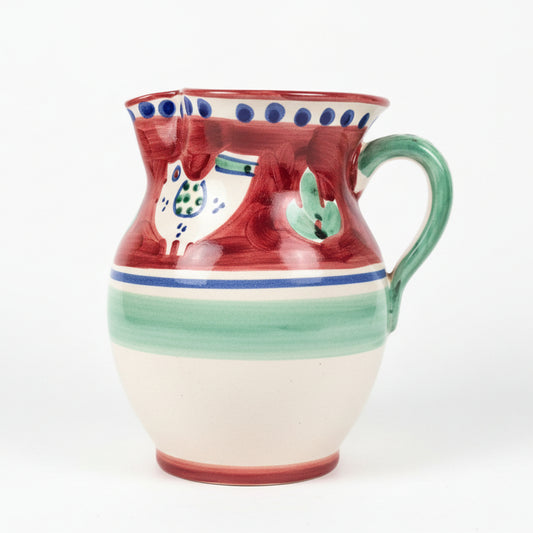 Ceramic pitcher with red, green, and blue patterns on a wooden surface
