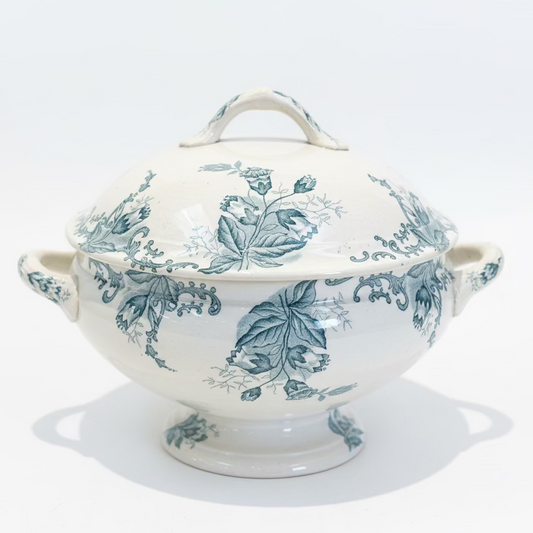 Decorative white tureen with blue floral pattern on a dark surface