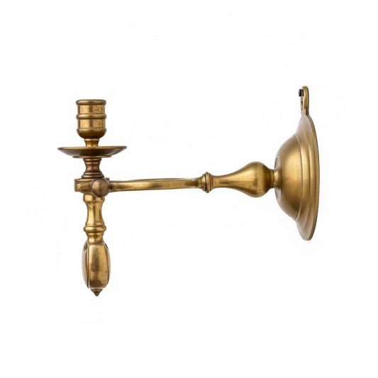 Brass wall-mounted candle holder on a textured wall