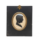 Silhouette portrait in a black frame with gold border on a cluttered surface.